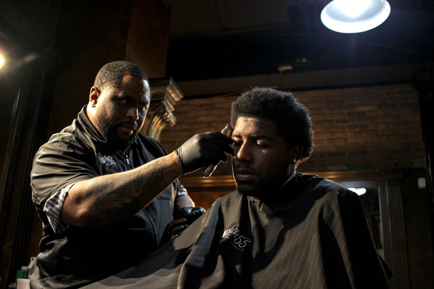 Barbeiro aparando o cabelo de um cliente na cadeira